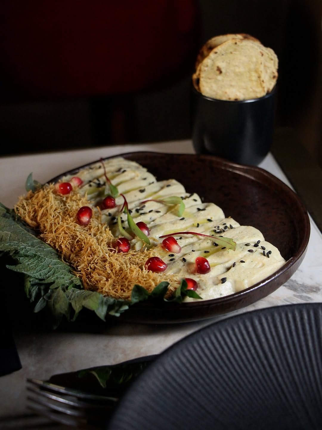 Chickpea shiso dip topped with pomegranate seeds and fried vermicelli, served with stacked pita